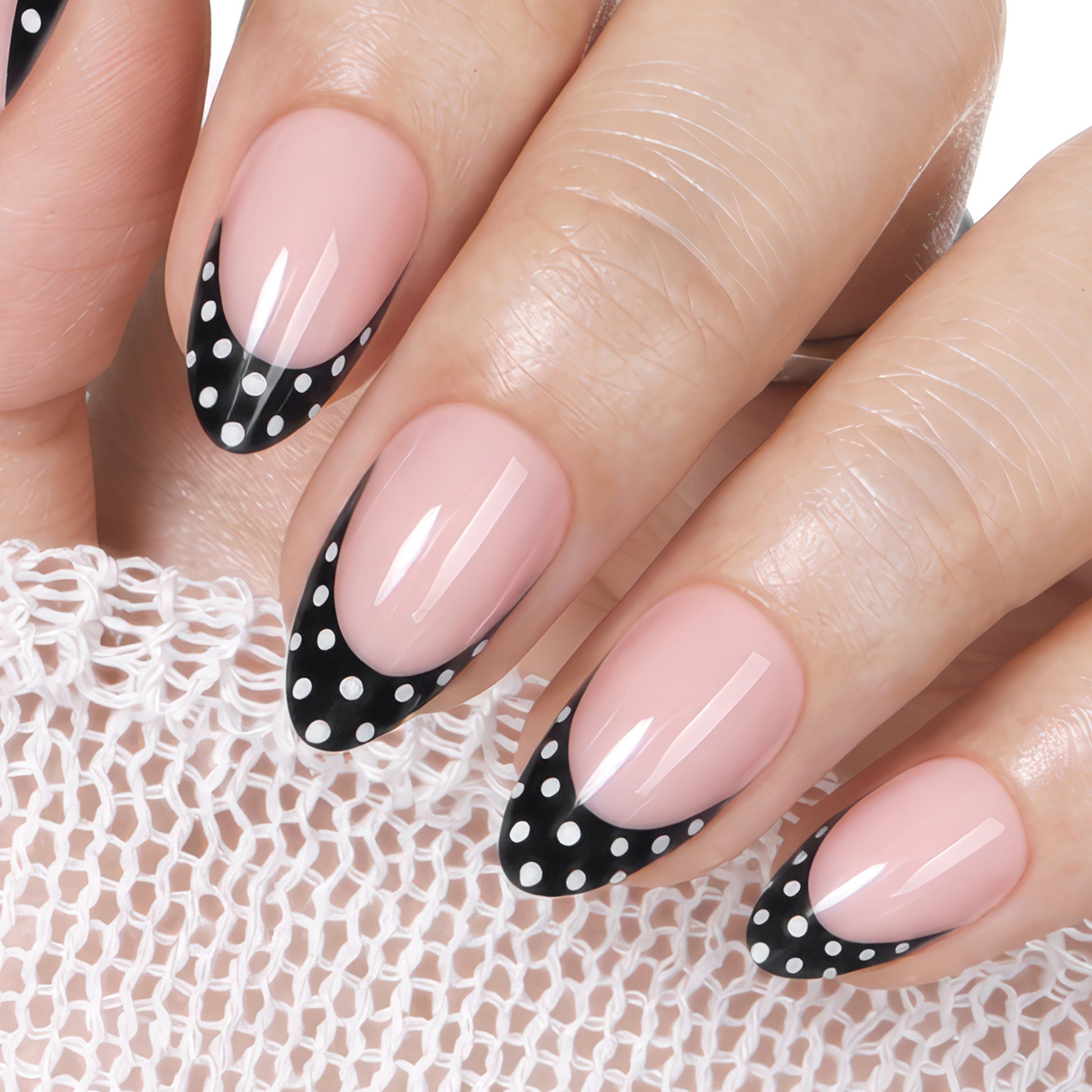Medium-length soft gel press-on nails with black French tips and white polka dots on natural pink base.