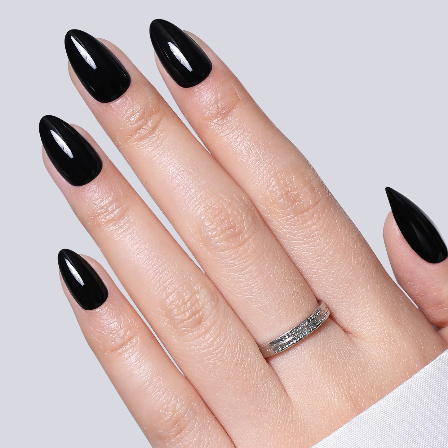 Black almond-shaped press-on nail tips by UNA GELLA, reusable gel false nails in 16 sizes, 32-piece set.