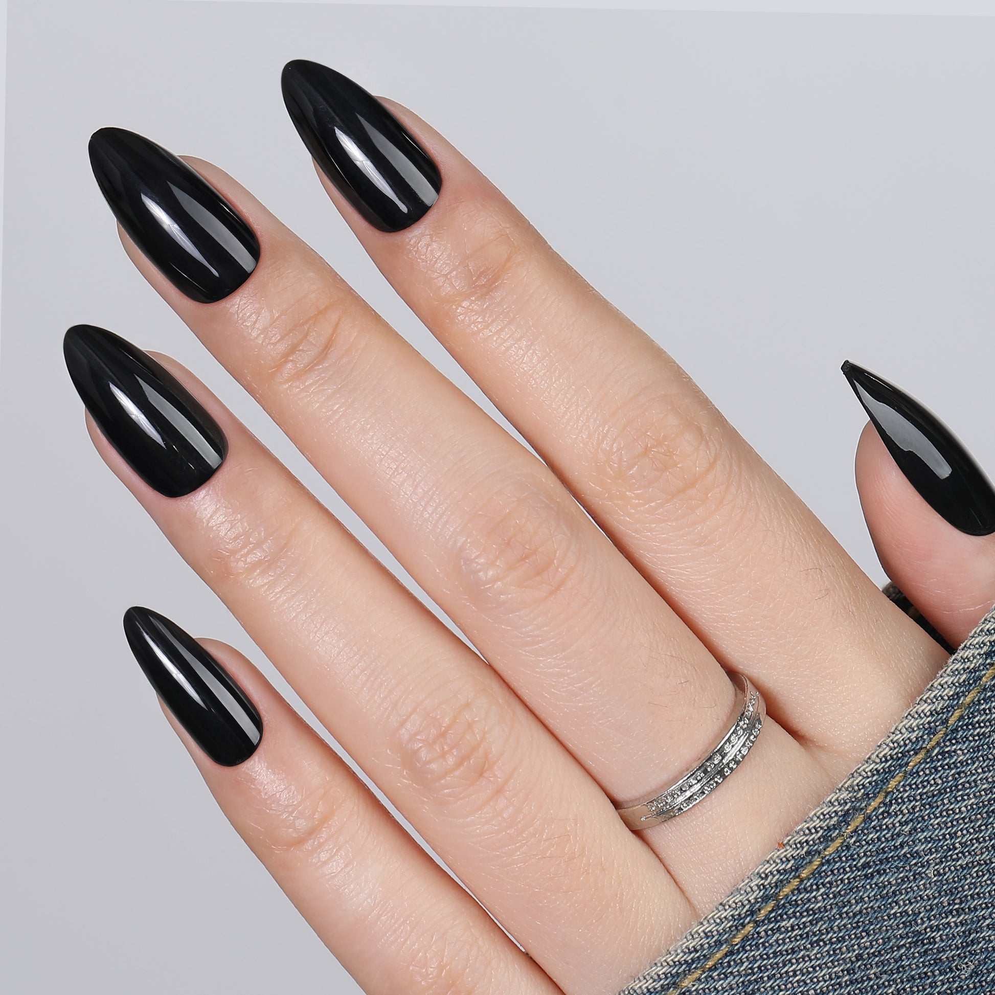 Medium almond-shaped black press-on nail tips by UNA GELLA, reusable soft gel, 32-piece set for DIY manicures.
